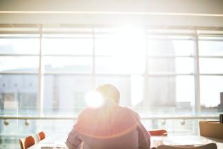 man sitting on chair in front on window during daytime by Bethany Legg courtesy of Unsplash.