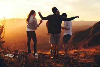 four people standing on edge of mountain by Helena Lopes courtesy of Unsplash.