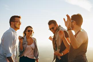 three men and one woman laughing during daytime by Helena Lopes courtesy of Unsplash.